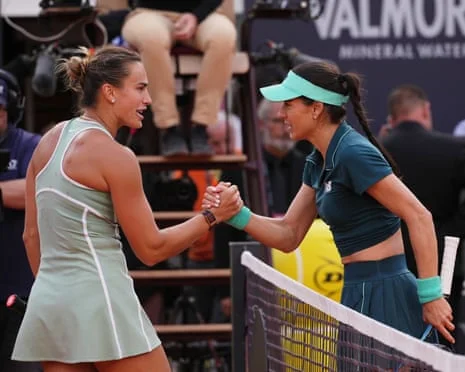 Romania's Sorana Cirstea and Aryna Sabalenka lock hands over the net