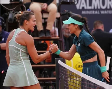 Romania's Sorana Cirstea and Aryna Sabalenka lock hands over the net
