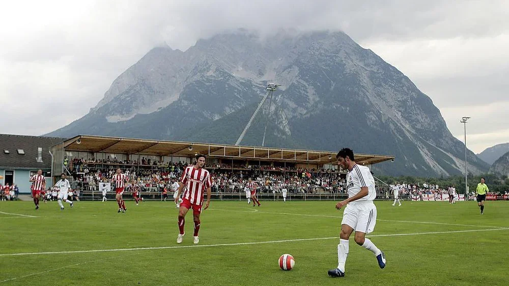 Stoke City play Real Madrid in a small Austrian stadium next to a large mountain, which towers over a low stand of seats
